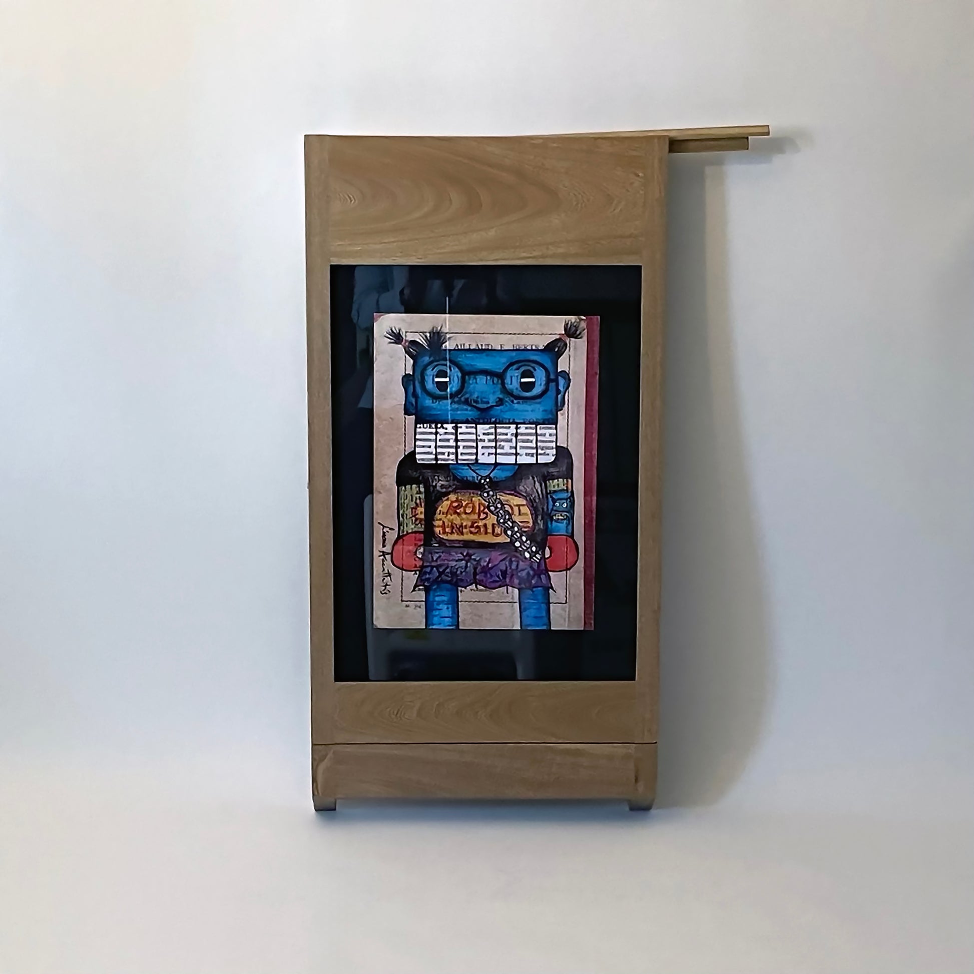 PicChair in natural oak; view of chair folded up as a frame with art on the wall. shows picture slot cover .